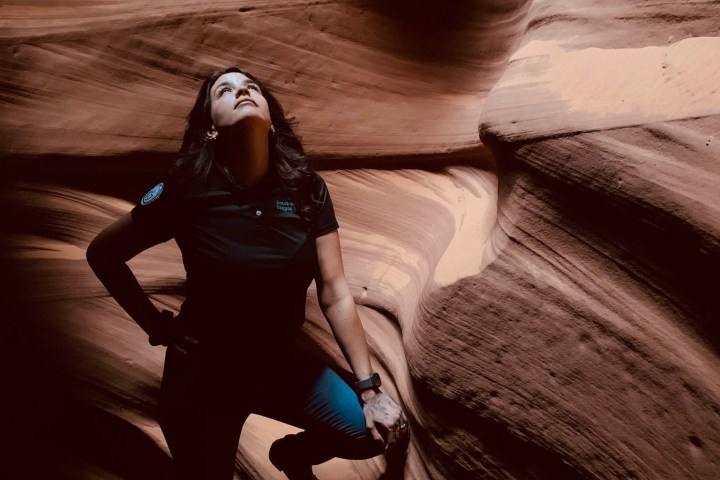 Person standing in narrow, wavy rock canyon looking upwards.