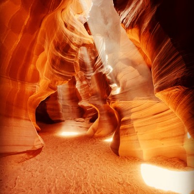 Sunlight illuminates a winding sandstone slot canyon passage.
