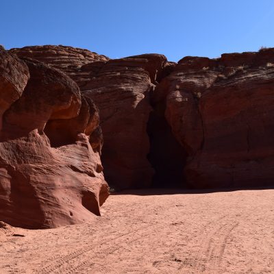 Red rock canyon cliff under blue sky, textures visible.