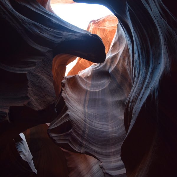 Sunlight illuminating smooth, wavy rock formations in a canyon.